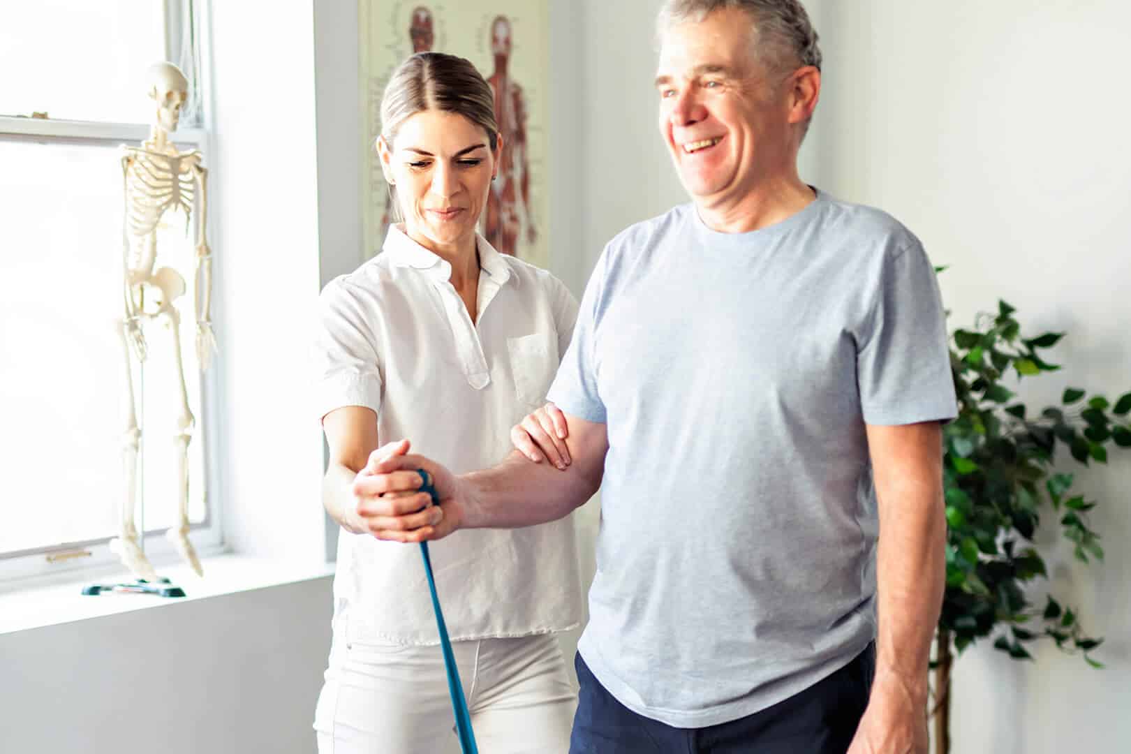 Female caregiver supporting older man, rehab