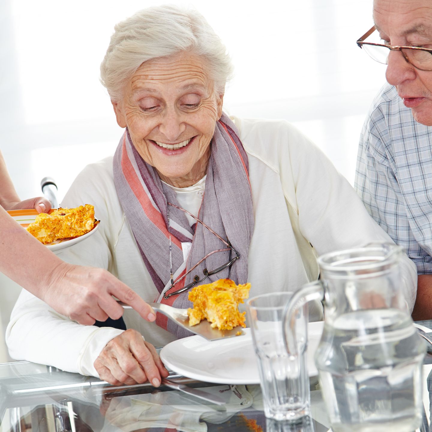 Caregiver serving food to a senior woman