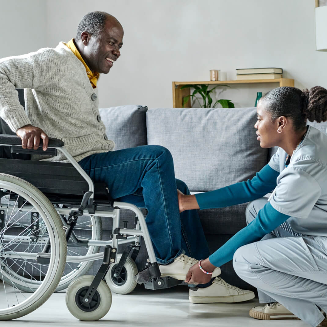 Female healthcare professional working with older male in wheelchair
