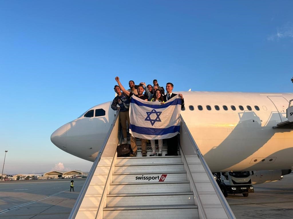 Group of people, holding Israel flag, standing on airplane steps