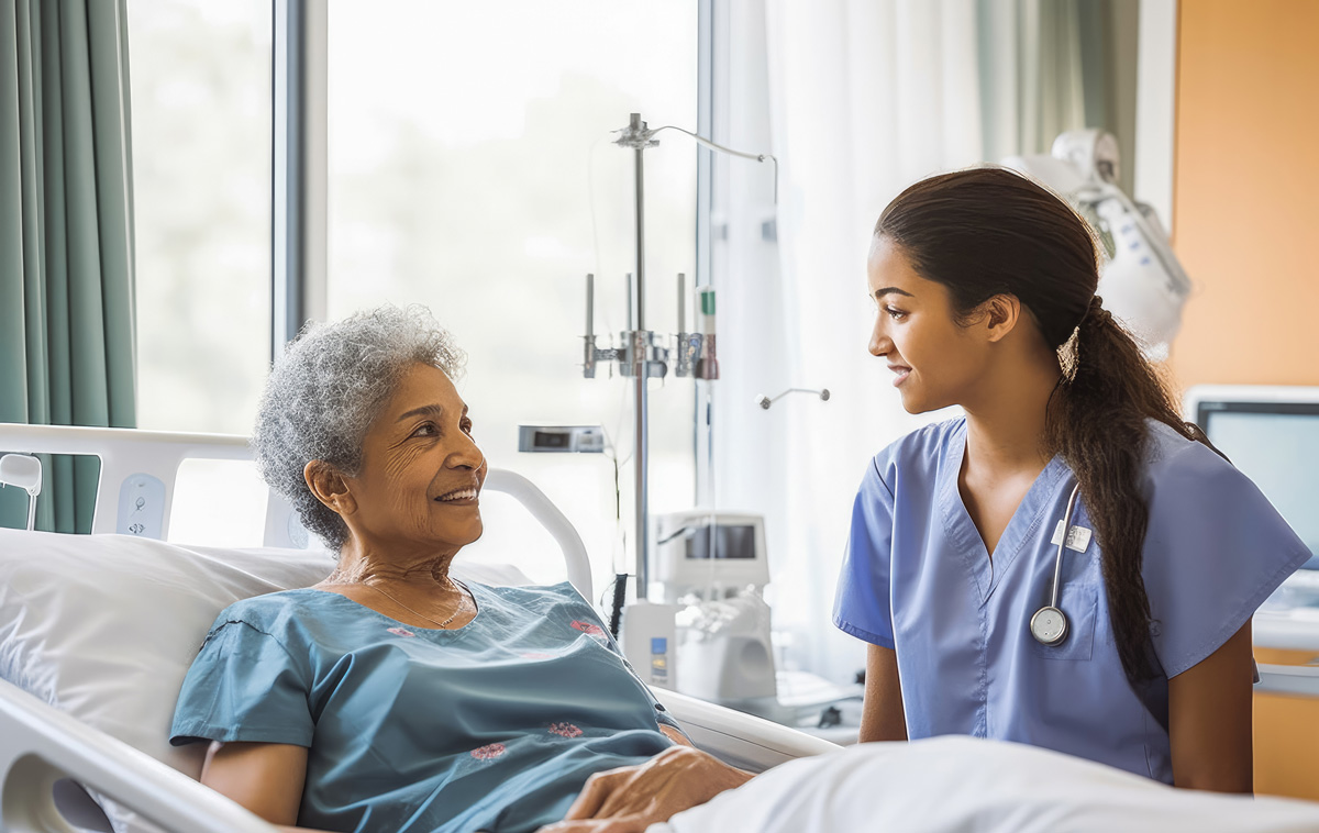 Female caregiver supporting older woman in hospital bed
